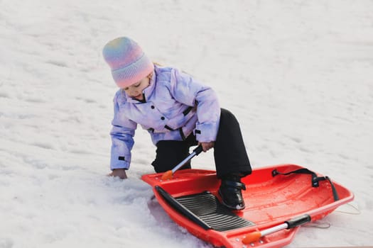 A girl with red bob sledding in the snow