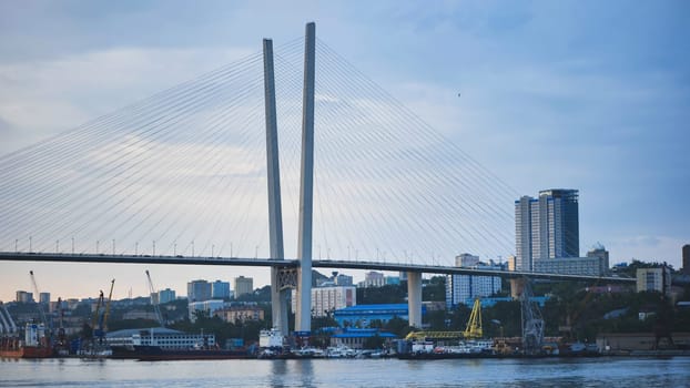 Golden horn bay cable stayed bridge connecting vladivostok's urban landscape, featuring modern cityscape, industrial cranes, maritime vessels in russian far east