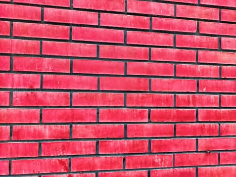 Vivid red brick wall showcases a structured pattern and provides ample copy space for customization or artistic projects.