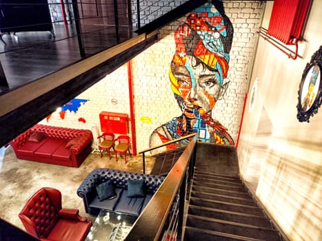 Kazan, Russia - July 04, 2024 - Vibrant mural adorns the wall of a loft-style hotel lobby in Kazan, creating an inviting atmosphere with stylish seating arrangements.
