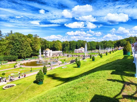 Peterhof, Russia - August 01, 2024 - Tourists explore Peterhof Park, admiring the elaborate fountains and lush greenery under a bright blue sky in St. Petersburg.