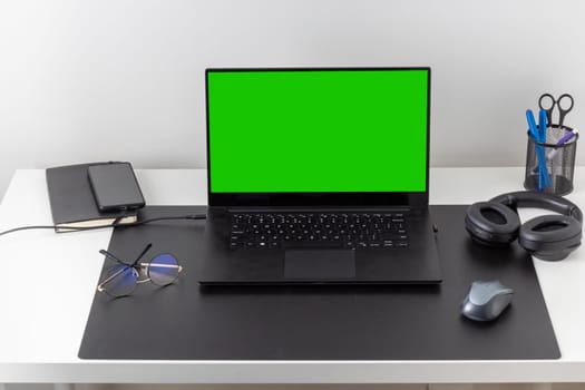 Laptop computer, notebook, and eyeglasses and headphones on a desk, place for work and study, home freelancer's office