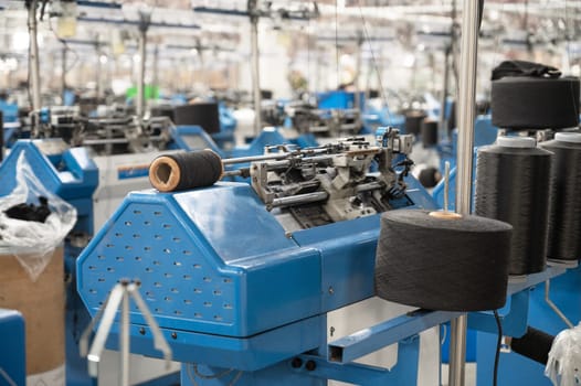 View of automated textile manufacturing machines in a factory, with spools of white thread ready for processing.