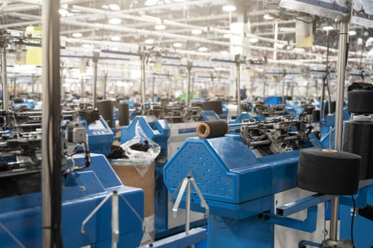 View of automated textile manufacturing machines in a factory, with spools of white thread ready for processing.