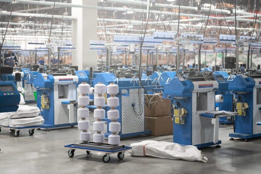 View of automated textile manufacturing machines in a factory, with spools of white thread ready for processing.