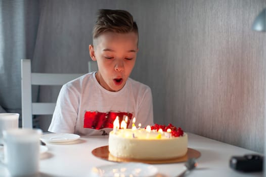 Smiling young boy leaning on a table with a lit birthday cake, enjoying a joyful celebration in a cozy setting.