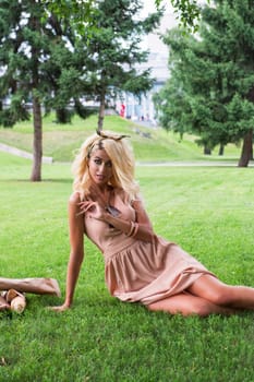 Rest in park, outdoor, people and leisure concept - beauty blonde alone young woman resting in the park