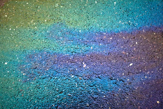 Gasoline creating rainbow chemical spill on asphalt road surface