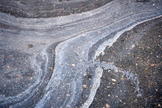 Gasoline or oil creating an abstract pattern on wet asphalt road.