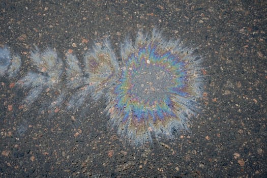 Gasoline or oil spill creating rainbow pattern on asphalt road