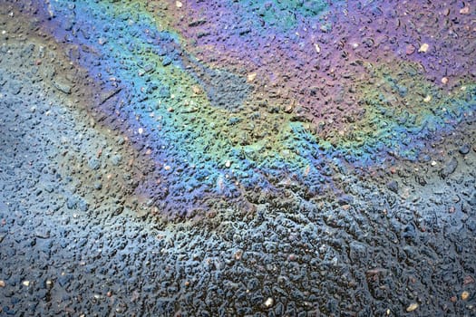 Macro image of colored oil spills on the asphalt, emphasizing the intricate patterns and colors that serve as a textured backdrop.