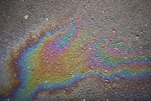 Radiant oil stain casting a colorful sheen on a rain-washed pavement
