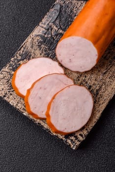 Delicious fresh ham cut into round slices with salt, spices and herbs on a dark concrete background