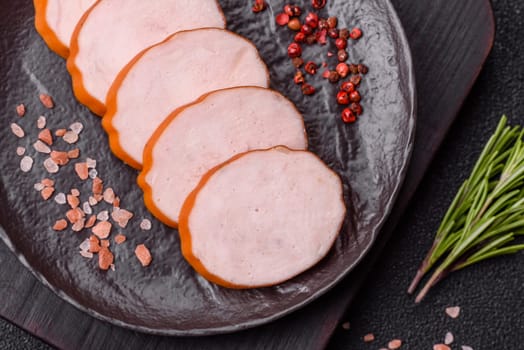 Delicious fresh ham cut into round slices with salt, spices and herbs on a dark concrete background