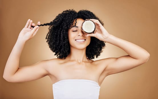 Woman, hair and coconut with shine and beauty, organic salon treatment for strong texture on studio background. Face, skin and natural cosmetic product for growth, haircare and fruit with smile.