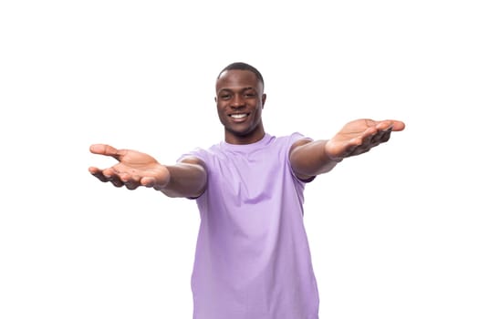 young friendly carefree american man dressed in a lilac cotton T-shirt on a white background with copy space.