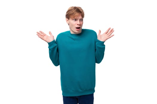 handsome redhead young man in blue sweater shows surprise.