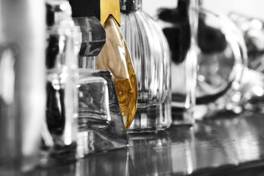 perfume bottles, some full and some empty, lined up on a wooden sideboard