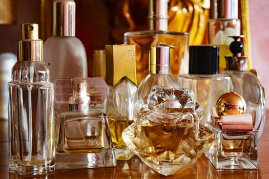 perfume bottles, some full and some empty, lined up on a wooden sideboard