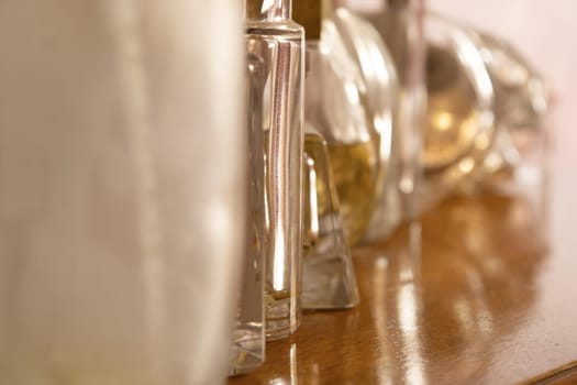 perfume bottles, some full and some empty, lined up on a wooden sideboard