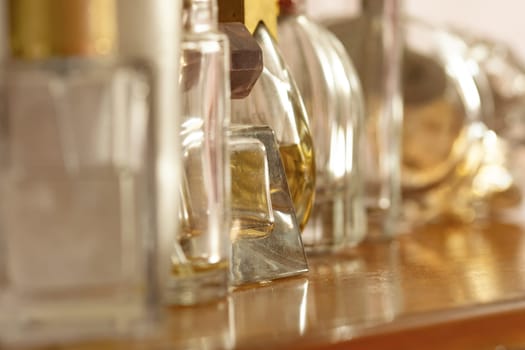 perfume bottles, some full and some empty, lined up on a wooden sideboard