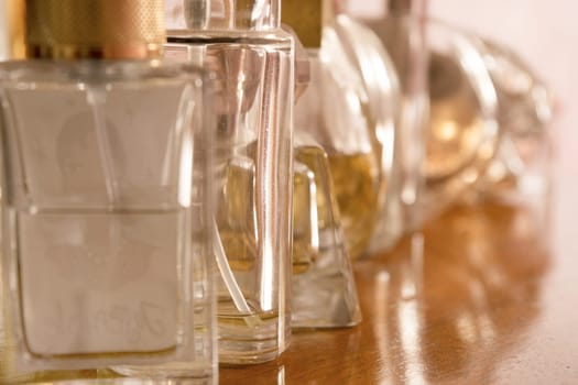 perfume bottles, some full and some empty, lined up on a wooden sideboard