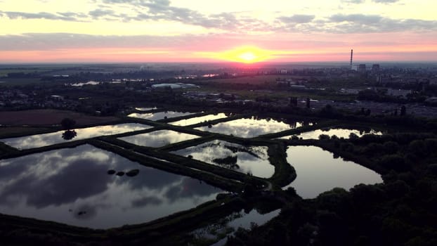 Aerial drone view flight over fish farming rates lakes. Fish Farming. Agricultural pond for breeding fish. Growing and fishing on fish farm. Mirror reflection of water. City. Industrial Zone