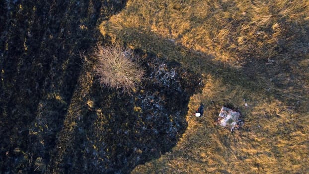 Aerial view Fire extinguishing. Fireman extinguishing burning dry grass. Open flames of fire and smoke. Yellow dry grass and black ash from burnt plants.Ecological catastrophy. Fire on field in steppe