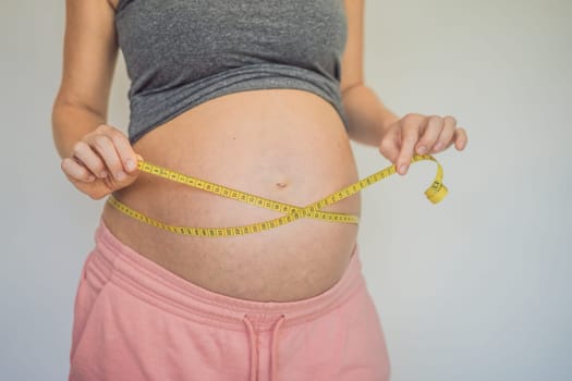 Young woman measuring her pregnant belly with centimeter tape. Centimeters European standard. Preparation for childbirth, Girl big belly advanced healthy pregnancy.