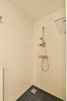 a bathroom with tiled walls and black tile flooring on the shower wall, there is a toilet in the corner