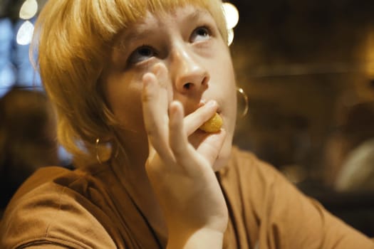 Teen girl eats delicious cheese sticks in a restaurant, enjoying. Close-up.