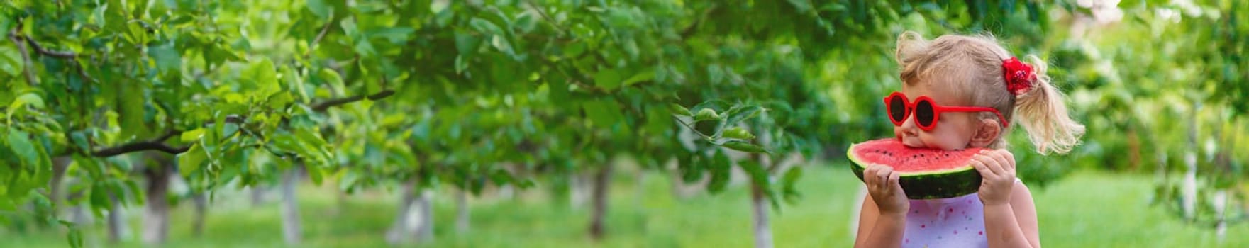 A child eats a watermelon in the park. Selective focus. Food.