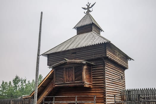 Historic wooden watchtower featuring double headed eagle emblem, representing imperial russian architectural heritage inside stone fortress walls