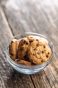 Chocolate chip cookies in bowl on a wooden table.