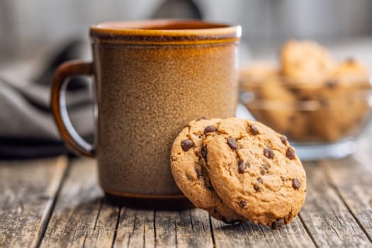Chocolate chip cookies and mug on a wooden table.
