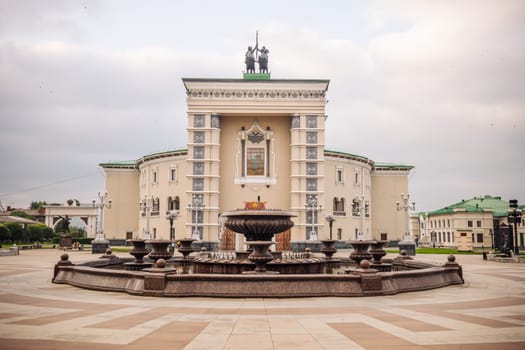 Musical theatre complex rising dramatically near ornate fountain in yoshkar ola, russia, showcasing architectural grandeur of regional cultural landmark