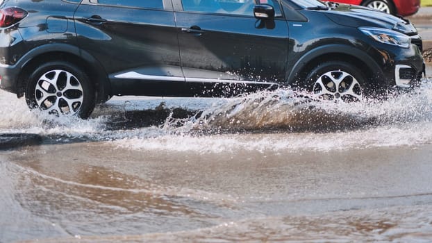 Suv driving through a large puddle, sending water splashing in all directions after a heavy downpour, showcasing the challenges of wet roads