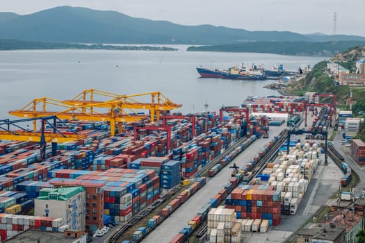 Freight trains carrying shipping containers near cargo cranes, illustrating global logistics and international trade transportation network