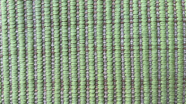 Close-up of a green woven fabric featuring intricate patterns and textures.