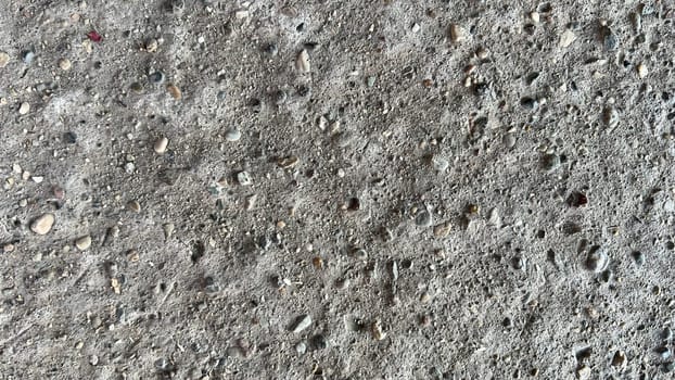 Close-up view of a concrete surface showcasing its rough texture and embedded stones.