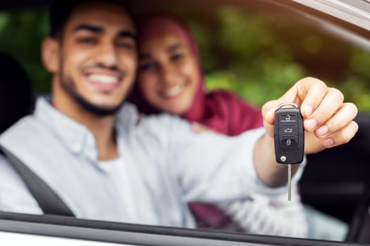 Test drive transport. Glad happy millennial arab woman in hijab and man show keys from new car, enjoy to purchase, couple have fun together, blurred. Buying own auto, credit, ad and offer, copy space