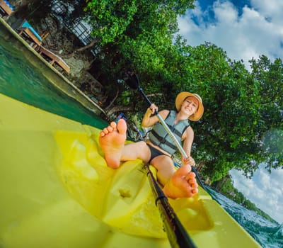 Unaltered woman tourist kayaking on the serene turquoise waters of Lake Bacalar, Mexico, surrounded by natural beauty. Adventure, relaxation, and outdoor travel concept in a peaceful tropical destination.
