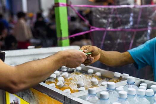 Tourist giving malaysian ringgit money to a malaysian seller to buy fresh juice in the Jalan Alor street food