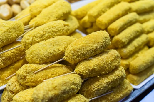 Many snacks and seafood in vietnamese night market in food festival, sign "meat rolls, price 15 000 dongs"