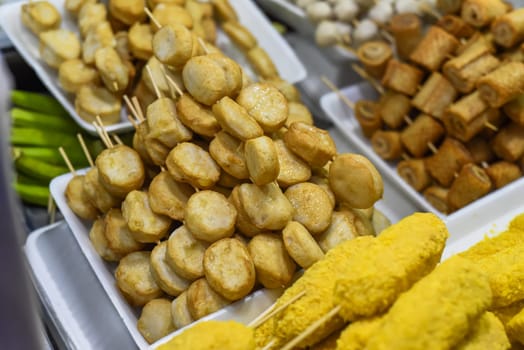 Many snacks and seafood in vietnamese night market in food festival, sign "beef ball, fish ball, price 10 000 dongs"
