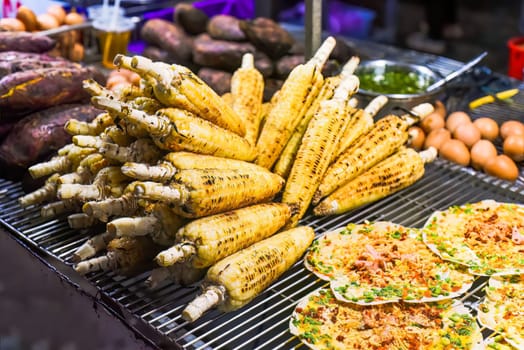 Grilled corn near vietnamese pancake with eggs, sausages and sauces in vietnamese night market in Da Lat