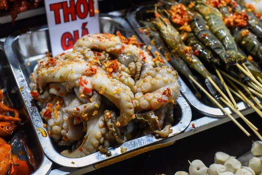 Many snacks and seafood in vietnamese night market with signs with vietnamese text "time, price" translation