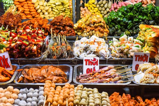 Many snacks and seafood in vietnamese night market with signs with vietnamese text "time, price" translation
