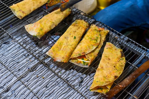 Grilled vietnamese pancake with eggs, sausages and sauces in vietnamese night market in Da Lat