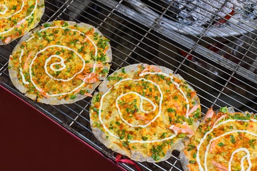Grilled vietnamese pancake with eggs, sausages and sauces in vietnamese night market in Da Lat